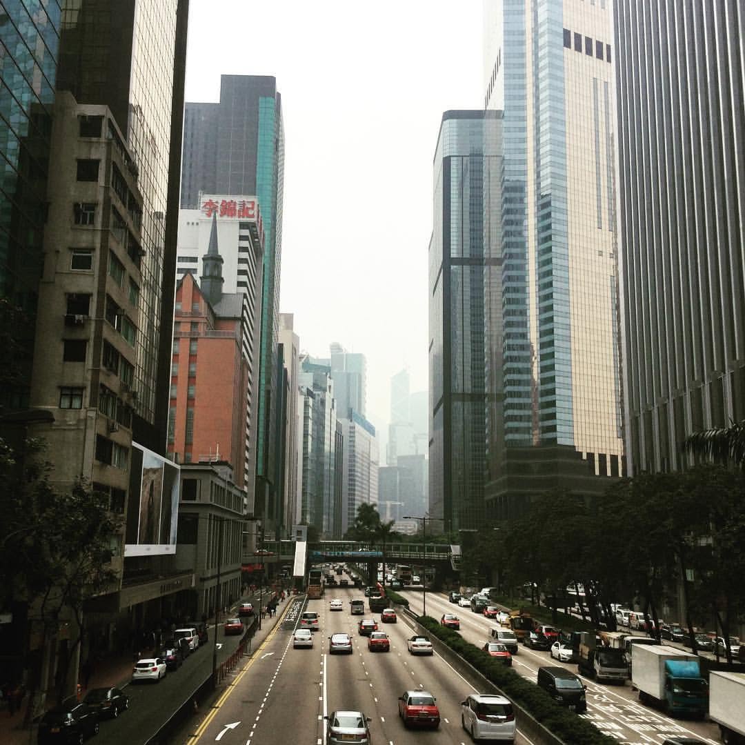 A hazy multi-lane city street running between glass towers